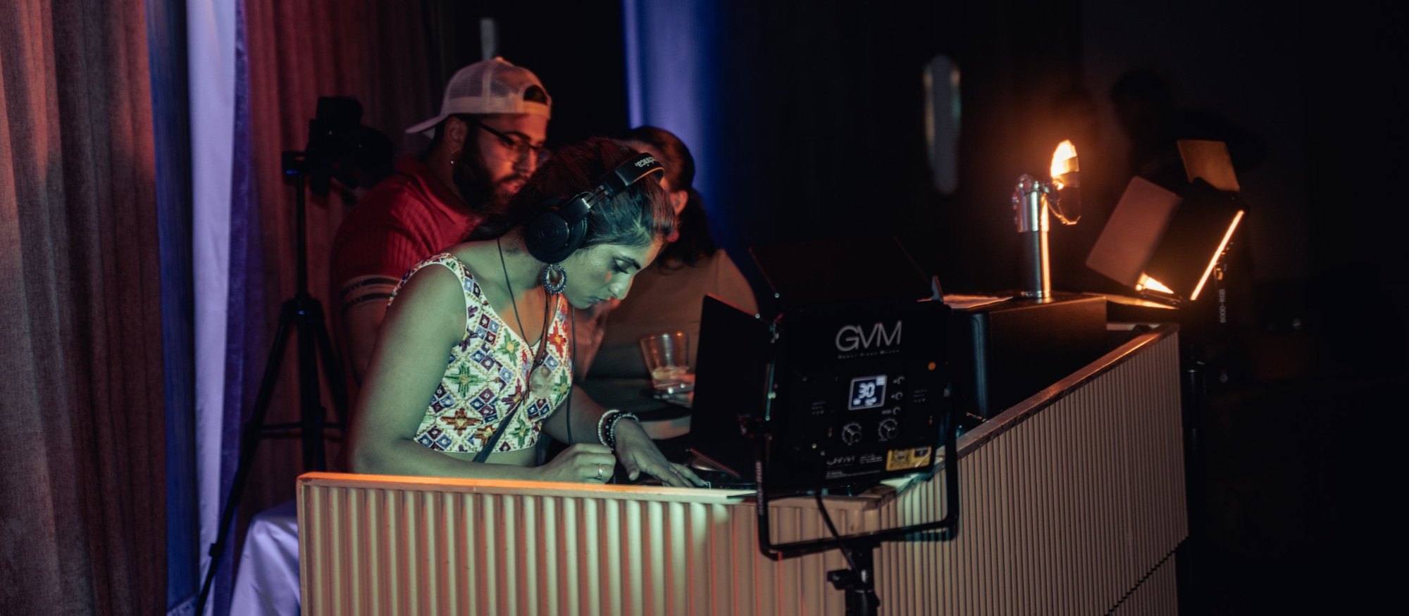 A DJ in headphones at the ribbed wooden booth under warm light at The Penthouse at Elsie